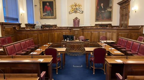 Inside the Guernsey States Chamber with leather-backed chairs and benches