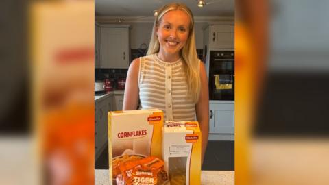 Annalise Jones, mewn top streipiog, gyda cornflakes a pasta o'i blaen