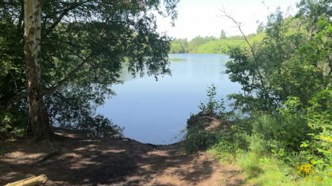 Swanholme Lakes in Lincoln. There is earth and greenery in the foreground.