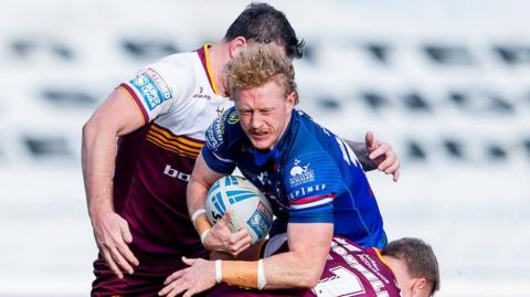 Wakefield Trinity's Lachlan Walmsley drives into the tackle of Huddersfield's Asher O'Donnell