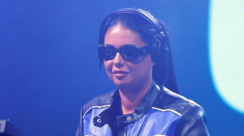 DJ Hannah Laing, wearing sunglasses and smiling as she performs at ˿ Radio 1's Big Weekend in Luton in 2024