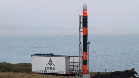 Rocket next to a Skyrora sign, with sea in the background.