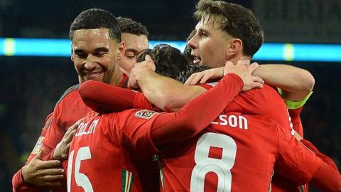 Wales players surround Liam Cullen to celebrate