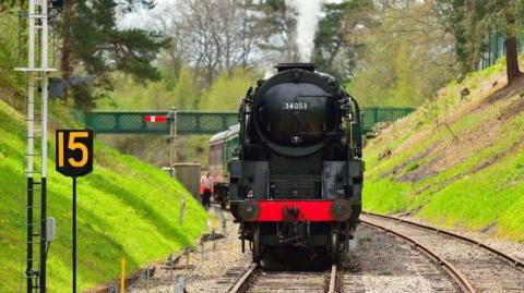 A black and red heritage train travelling on the line. 