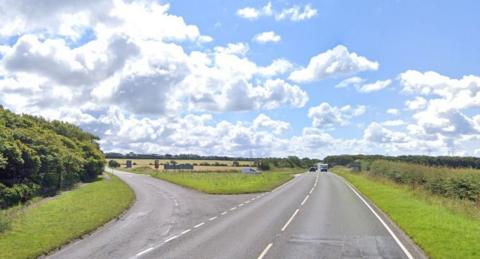 A Google Maps streetview image of the junction of Branthwaite Road and the A596. There are fields and trees either side of the roads.