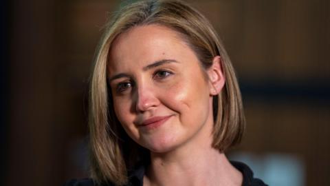 Head shot of a smiling woman with blonde bobbed hair