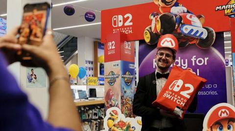 A customer takes a photograph with a Nintendo Switch 2 display board during the sale launch of the gaming console on Oxford Street in London early on 5 June 2025.