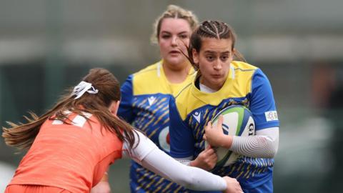 Gwalia Lightning player in blue and yellow is tackled by an Edinburgh player in orange