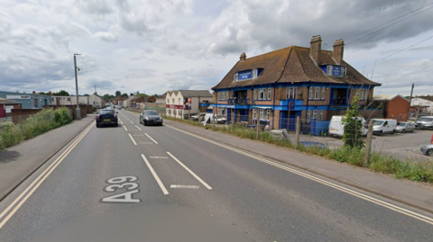 A view of the A39 in Bridgwater near an industrial estate. Some cars are driving on the road.