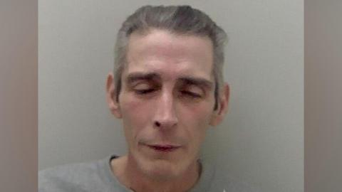 Mark Jesse with his eyes closed in a grainy police mugshot