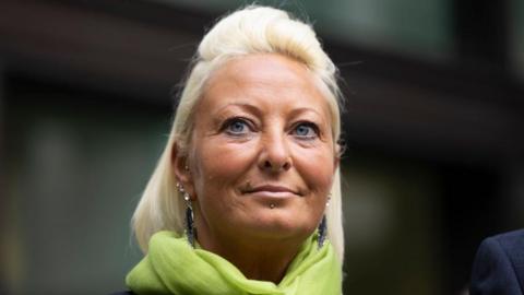 Charlotte Charles looking into the distance with a green scarf and slight smile