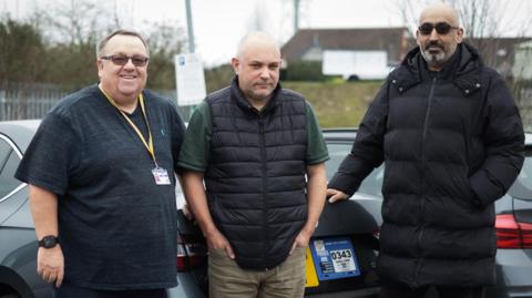 Darren Fitchett, Lee Roach and Manpreet Singh Malhi stood in front of taxi vehicles