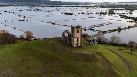 An old ruined church sits on top of a hill overlooking flooded hills in Burrowbridge, Somerset. 
