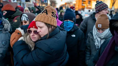 Women hug in the streets of Minneapolis after a fatal shooting by immigration officers.