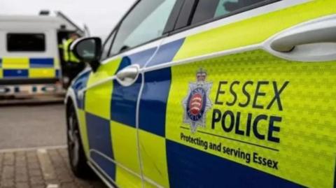 A Essex Police car parked in a bay. There is a police van in the background 