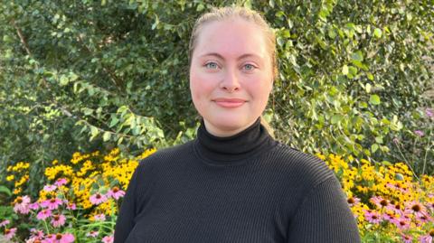 Bianca Chivu wearing a black long sleeved top and standing behind flowers