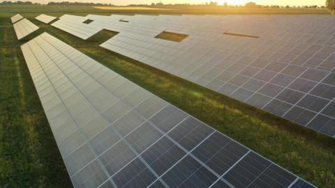 A solar farm with a sun setting in the background