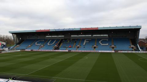 A shot of the pitch and a stand at Carlisle's Brunton Park with the letters 'CUFC' in white on the seats