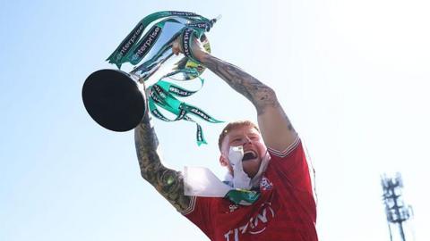 Josh Stones hoists the National League trophy in the air as he celebrates winning the title and promotion to the EFL with York City after their dramatic 1-1 draw with Rochdale in April.