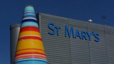 A colourful cone sculpture stands next to the grey facade of St Mary's Hospital.