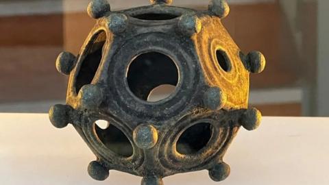 Close-up shot of the 12-sided artefact with varying sized holes and rounded small balls protruding from its surface