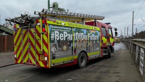 A Suffolk Fire and Rescue Service fire engine on a road, the rear of the vehicle is pointing towards the camera.