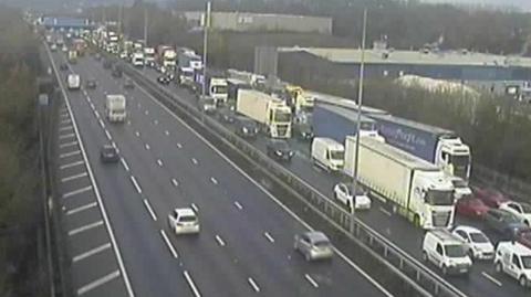 A traffic camera showing queuing traffic in one direction on the M1 including multiple lorries