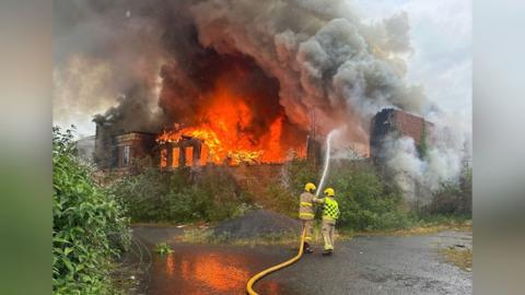 Firefighters spray water into the burning building 