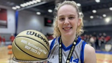 Harriet Welham poses with a National Cup medal and commemorative basketball