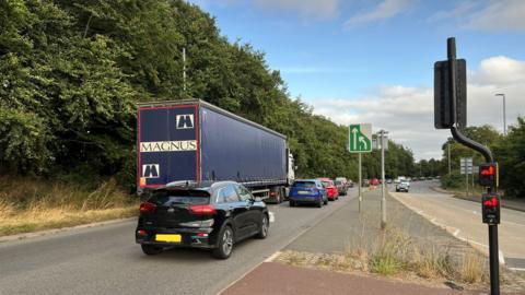 Picture of road and lorries merging in turn on the A358 with traffic lights visible in the foreground