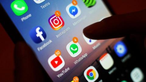 A number of apps including Facebook, YouTube, WhatsApp and Messenger are visible on the home screen on an iPhone. 