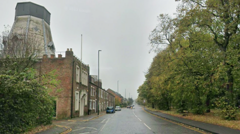A Google Street View shot of Claremont Road - a long road running adjacent to the A167. The stretch pictured shows a grassy area with trees down one side and terraced housing on the other side.