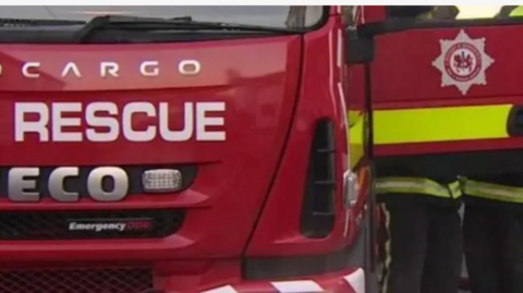 A fire engine is seen from the front with its door open.