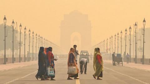 People cross the Kartavya Path, near India Gate in Delhi, with the area engulfed in a thick layer of smog in the morning mist of 27 October.