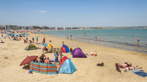 Weymouth Beach with crowds of people sunbathing.