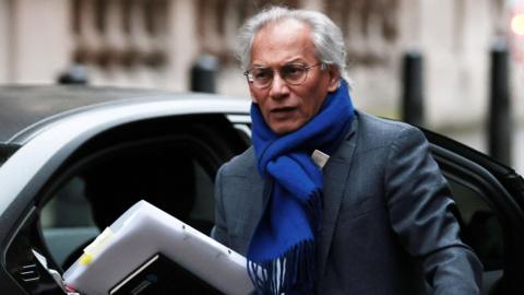 Samir Shah in a suit and bright blue scarf arriving for the committee hearing