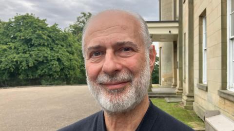 Fabian Hamilton, who has short grey hair and a grey beard. He has brown eyes and is smiling in the headshot.