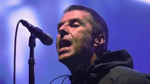 A closeup of Liam Gallagher singing into a microphone