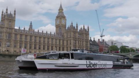An Uber Boat by Thames Clippers on the River Thames in front of the Palace of Westminster building.