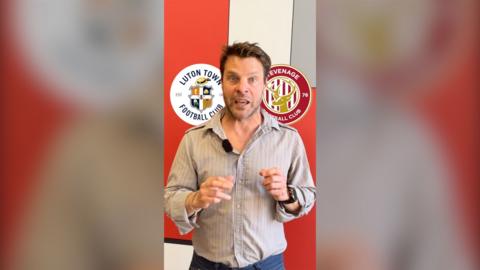 Geoff Doyle in a grey button shirt is staring at the camera. There are super-imposed images of the Luton Town Football Club crest next to the Stevenage Town FC crest. 