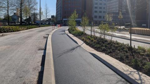 A freshly tarmacked cycle path alongside an existing road through Swindon town centre.
