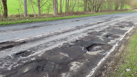 A view of a road near Southwell with temporary repairs alongside newer potholes.