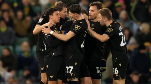 Oxford United players celebrate the 95th-minute equaliser at Norwich