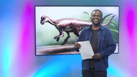 De-Graft in the studio with a dinosaur in the screen
