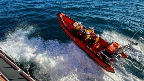 A lifeboat RIB with four crew on board at sea.