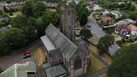 An aerial photograph of a church with houses and trees surrounding it 