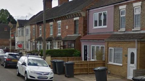 Exterior of the terraced properties on New Road - with cars parked on the street in front.