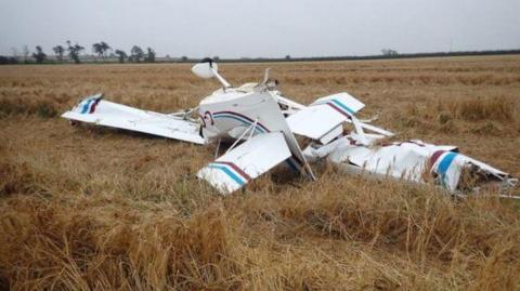 A picture of plane debris in a field. The white aircraft is a Eurofox 912(S).