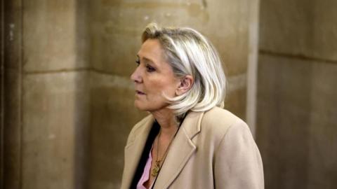 Marine Le Pen arrives at the Appeals Court, wearing a beige coat, pink shirt and a necklace 