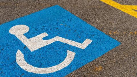 A blue disabled parking symbol painting on tarmac